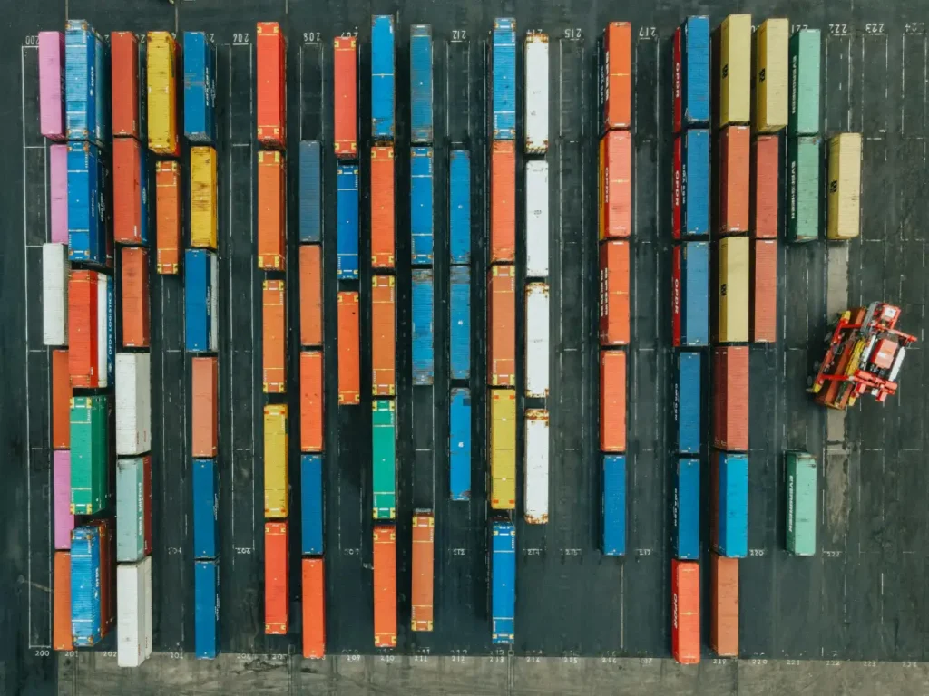 Foto udara kontainer kargo berwarna-warni di pelabuhan logistik, menggambarkan rantai nilai bisnis